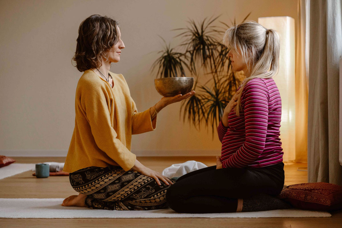 Linda sitzt einer Schwangeren gegen&uuml;ber und h&auml;lt eine Klangschale in der Hand