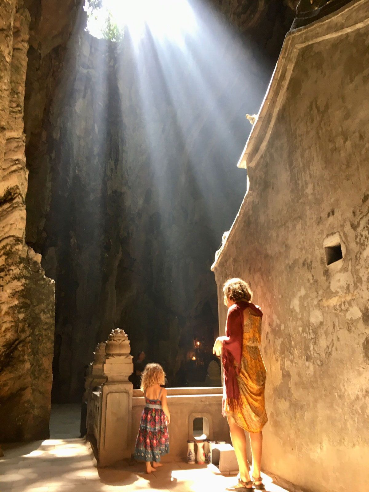 Mutter mit ihrem Kind steht in einer lichtdurchfluteten Höhle